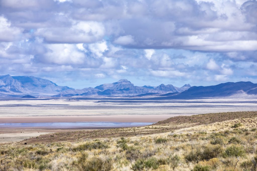 desert flats with mountains in background and cloudy skies above