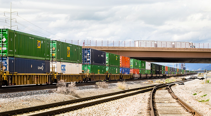 Shipping containers on flat bed trains moving along train tracks