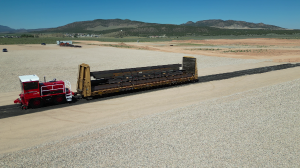 Train moving down rails across desert landscape